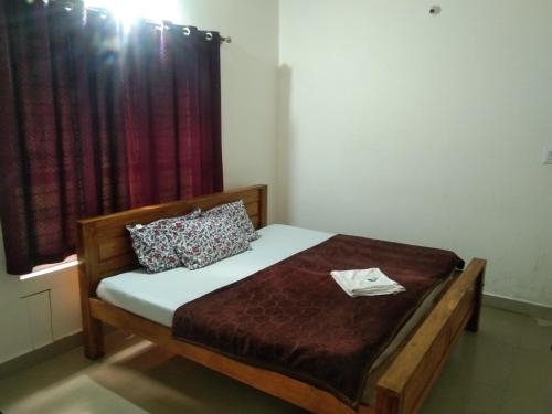 a bedroom with a bed with a wooden frame and a window at Brookfield estate villa 2bhk in Madikeri