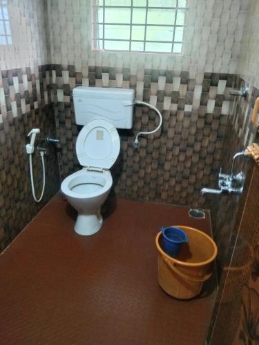 a bathroom with a toilet and a shower and a bucket at Brookfield estate villa 2bhk in Madikeri
