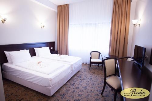 a hotel room with a bed and a table and chairs at Rediu Hotel & Restaurant in Botoşani