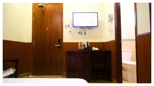 a bathroom with a toilet and a television on the wall at Nam Xuan Premium Hotel in Da Lat