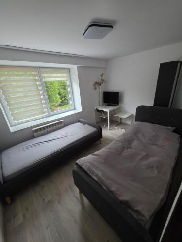 a bedroom with a bed and a window and a desk at Noclegi Pracownicze Niepołomice in Niepołomice
