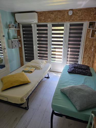two beds in a room with shuttered windows at Studette avec terrasse privée in Saint-Raphaël