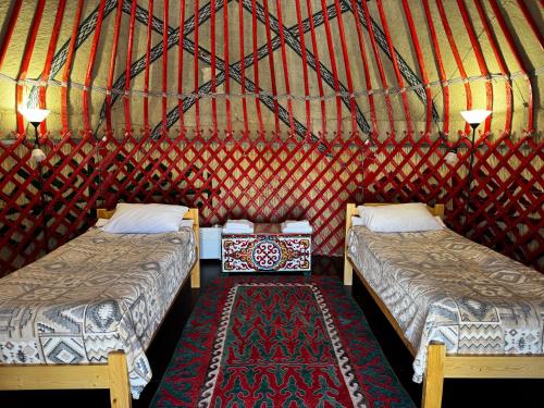 a room with two beds and a rug in a yurt at BarBulak Yurt Lodge in Bar-Bulak