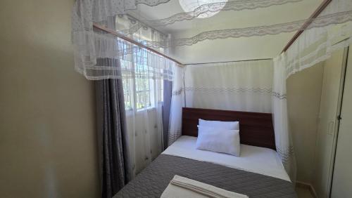 a small bed in a room with a window at Mambo Number Five in Entebbe