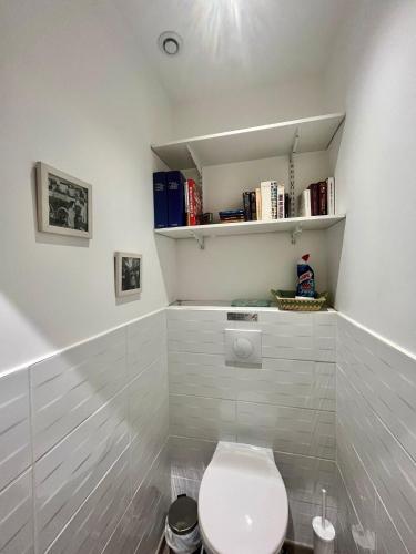 a bathroom with a toilet and books on shelves at gîte en rdc A 200 m tgv et de la fac A 400 m des places 250 places de parking face au logement in Arras