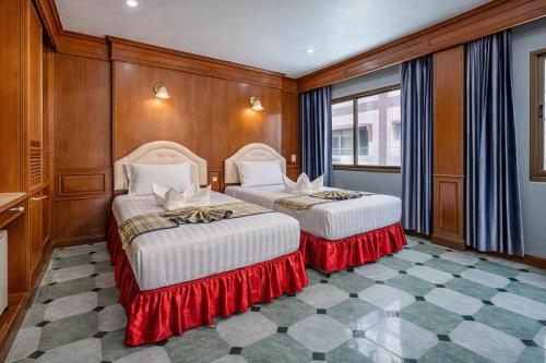 two beds in a room with wood paneling at Patong Social Hotel & Restaurant, Patong Beach in Patong Beach