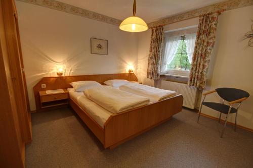 a bedroom with a bed and a window and a chair at Ferienwohnung Haus Rieder Inzell in Inzell