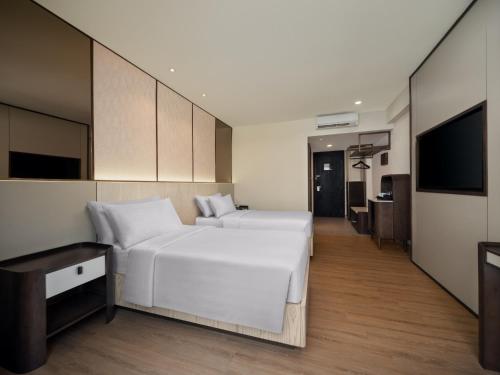 a bedroom with a large white bed and a flat screen tv at Aston Kuta Hotel and Residence in Kuta