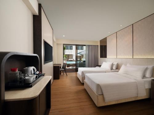 a hotel room with two beds and a television at Aston Kuta Hotel and Residence in Kuta