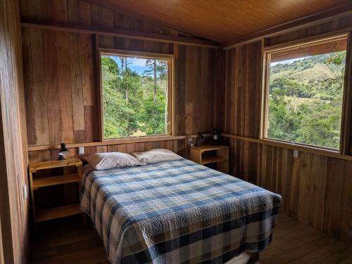 a bedroom with a bed and two windows at Rancho Ecojoya Paradise Mountain working farm in nature in San Isidro de El General