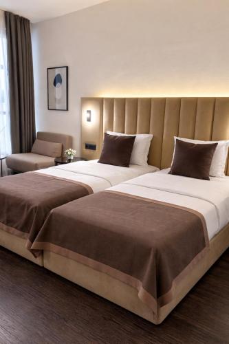 a hotel room with two beds and a chair at Bayer's City Hotel in Munich