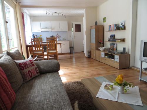 a living room with a couch and a table and a kitchen at Kastavengrund - Ferienhäuser mit Kamin in Lychen