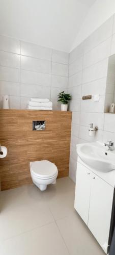 a white bathroom with a toilet and a sink at Umberto Apartamenty Dwupoziomowe Dąbki in Dąbki