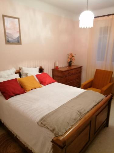a bedroom with a bed with colorful pillows and a chair at Chez Christine in Sarrancolin