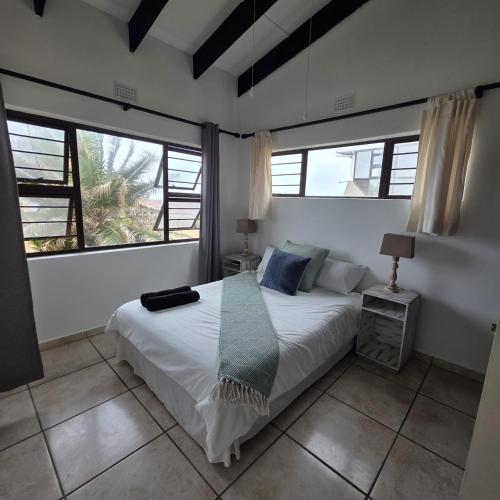 a bedroom with a white bed and two windows at Allesreg Holiday Home in Margate