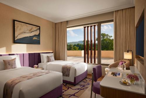 a hotel room with two beds and a large window at Vivanta Ekta Nagar in Kevadia