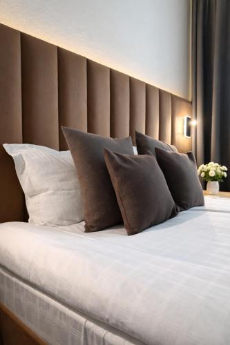 a large bed with white pillows and brown walls at Bayer's City Hotel in Munich