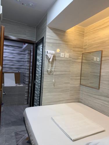 a room with a bed and a shower with a phone at Mabuhay INN in Hong Kong