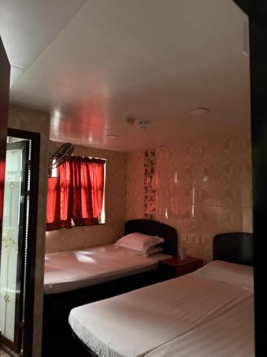 a room with two beds and a window with red curtains at Mabuhay INN in Hong Kong