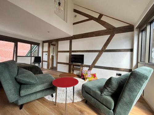 a living room with a green couch and a red table at D'r Preëksjtool in Eygelshoven