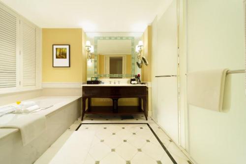 a bathroom with a tub and a sink and a mirror at Hangzhou Rose Garden Resort & Spa in Hangzhou
