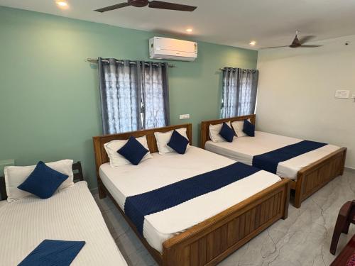 a bedroom with two beds with blue and white pillows at Teja Residency in Alāndurai