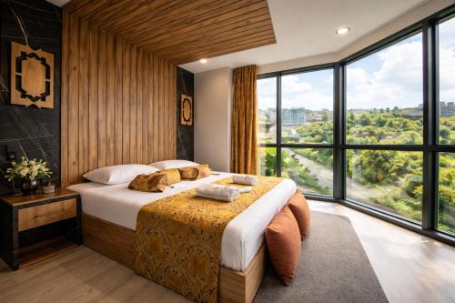 a bedroom with a large bed and large windows at Air Barbaros Hotel Trabzon in Trabzon