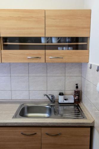 a kitchen with a stainless steel sink and wooden cabinets at Apartment Sučany in Sučany