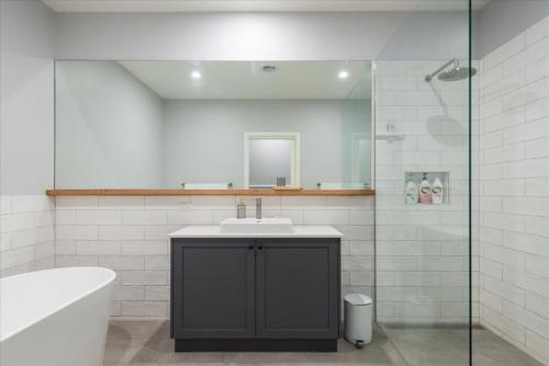 a bathroom with a sink and a tub and a mirror at Wilson's Beach Beauty in Inverloch
