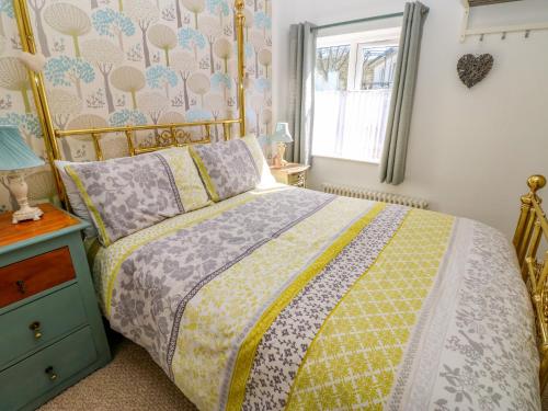 a bedroom with a bed with a yellow comforter and a window at The Museum in Alston
