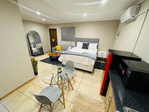 a bedroom with a bed and a living room at Hei Stays Bachelor Apartment in Bronkhorstspruit
