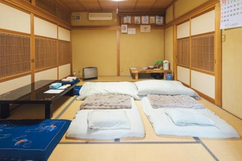 a room with three beds and a table in it at 魚沼ヒミツ基地 in Uonuma