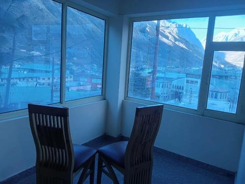 a room with two chairs in front of a window at Shree Kuber Regency in Badrinath