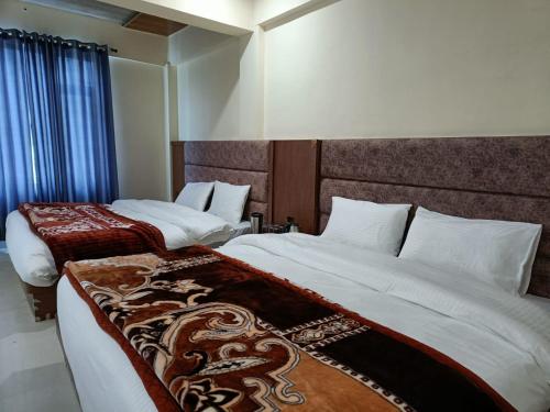 a bedroom with two beds with white sheets at Shree Kuber Regency in Badrinath