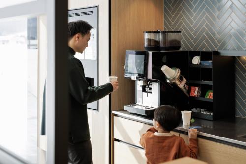 a man and a child standing in a kitchen with a microwave at Fairfield by Marriott Hokkaido Minamifurano in Minamifurano