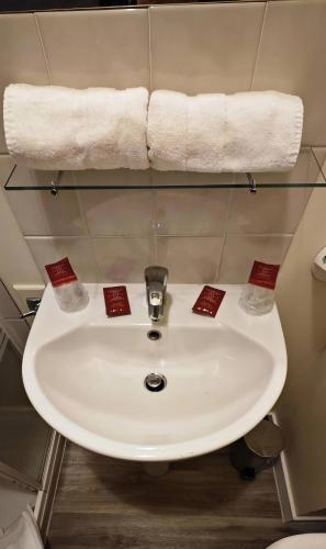 a white sink in a bathroom with towels at Hotel De France in Pontorson
