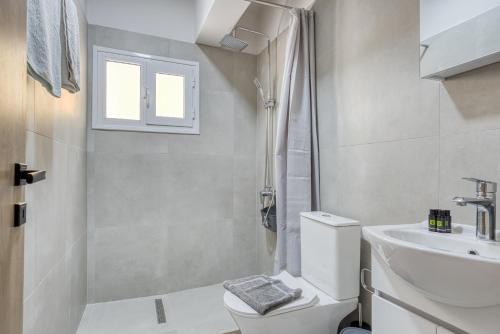 a white bathroom with a toilet and a sink at Rubick solari studio in Mantoúkion