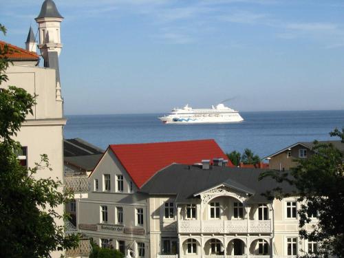 a cruise ship in the ocean behind a building at Villa Am Steinbach in Sassnitz