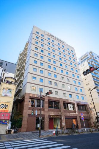 a tall white building on a city street with a traffic light at Hotel Keihan Asakusa in Tokyo