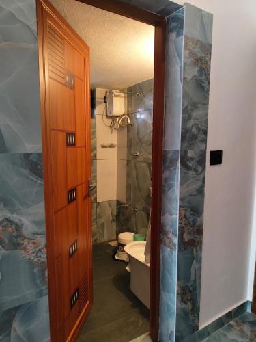 a bathroom with a toilet and a wooden door at RiverBank Gardens, Mananthavady, Wayanad in Mananthavady
