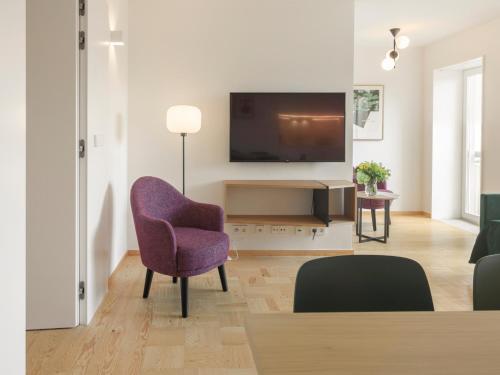 a living room with a tv and a purple chair at LSA Príncipe Real by Numa in Lisbon