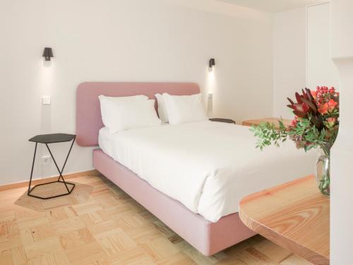 a bedroom with a large bed and a vase of flowers at LSA Príncipe Real by Numa in Lisbon