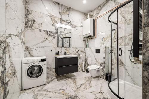a marble bathroom with a washing machine and a sink at Platinum Prestige Residence in Rybnik