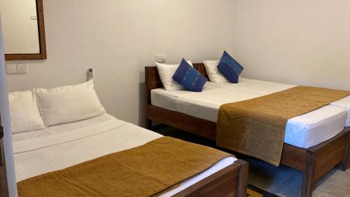 a room with two beds and a mirror at Joy Land Resort in Habarana