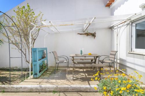 a patio with a table and chairs and a window at Casa Bettina in Vila Nova de Milfontes