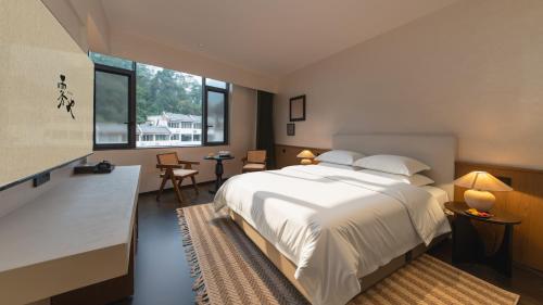 a bedroom with a large white bed and a large window at Wuye WOO YEAH Tangchi Hotel in Emeishan City