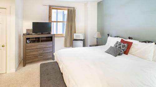 a bedroom with a white bed and a television at Cimarron Lodge 50 by AvantStay Ski-InSki-Out Property in Complex w Two Hot Tubs in Telluride