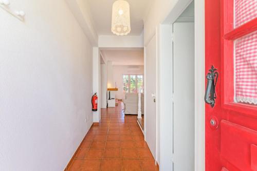 a hallway with a red door and a red tile floor at Casa Buganvília in Sines