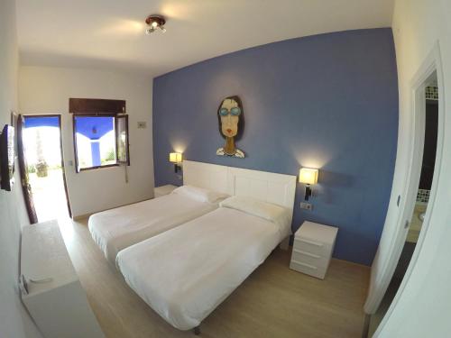 a bedroom with a large white bed with a blue wall at Arte Vida in Tarifa