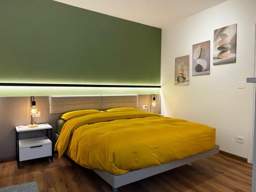 a bedroom with a yellow bed and a green wall at Casa Primavera in Agordo